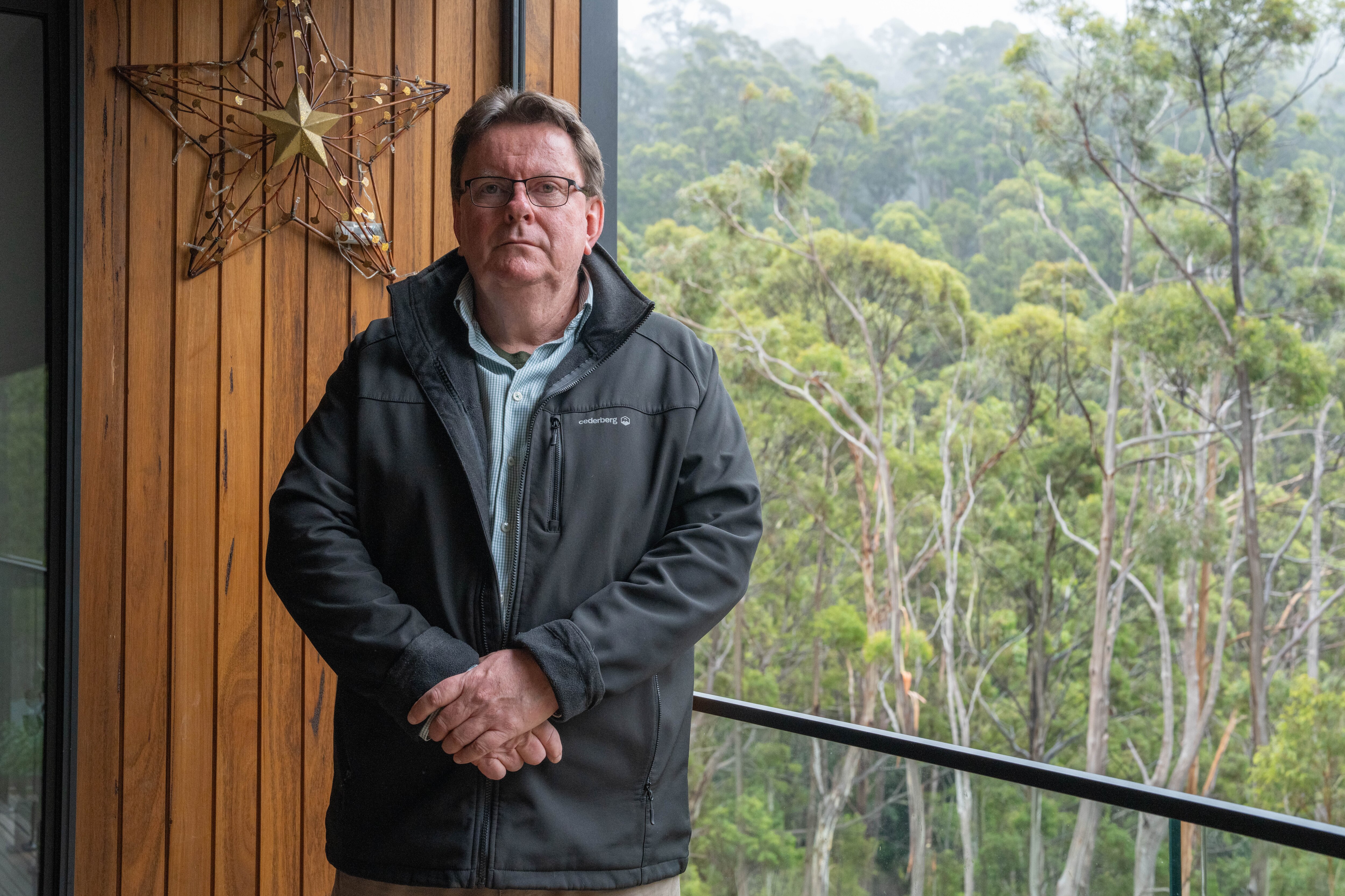 Man standing on the deck of his house.