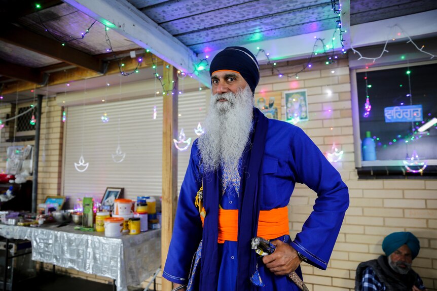 Manjit Diwali stands in a room filled with bright decorations.