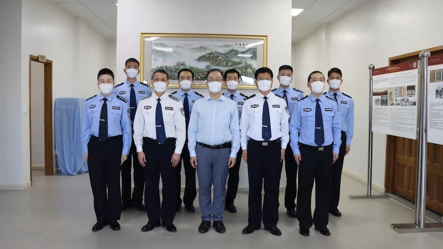 A group of uniformed men standard in a row inside an office space.