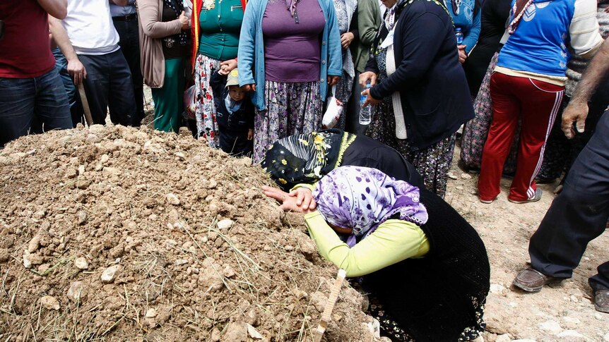 Women mourn during the funeral of a miner who died in a fire at a coal mine in Soma.