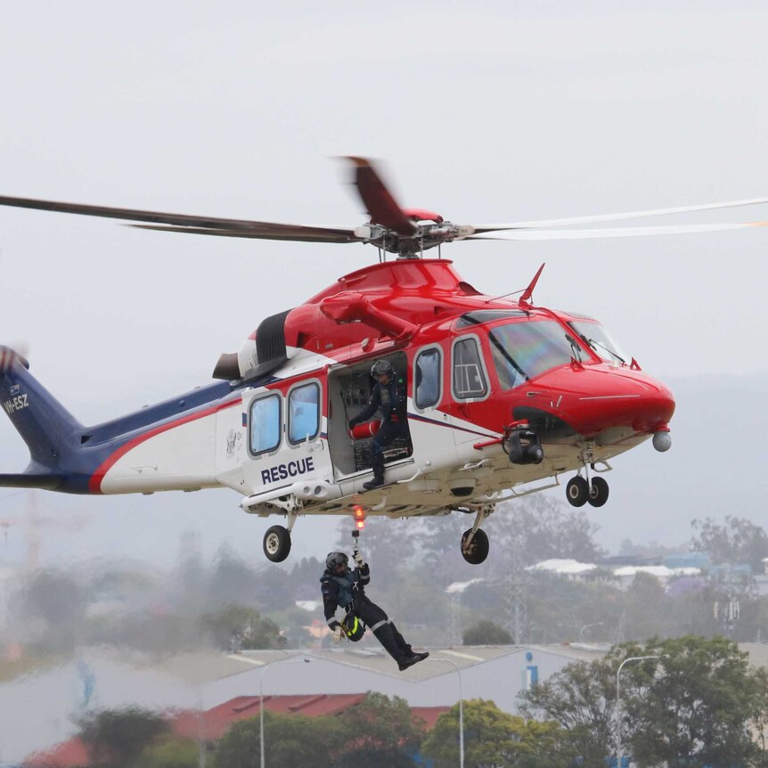 A rescue worker is winched out of a AW-139 VH-ESZ rescue chopper.