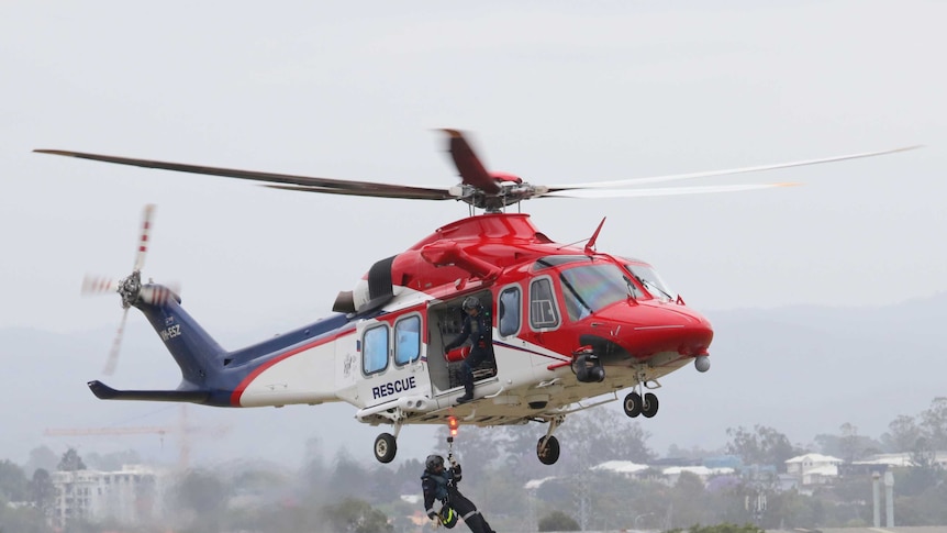 A rescue worker is winched out of a AW-139 VH-ESZ rescue chopper.