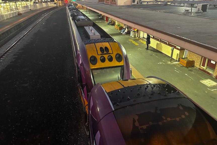 V-Line carriages sit alongside a railway station platform.