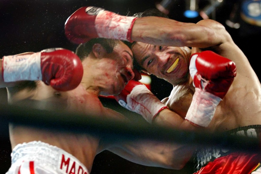 Manny Pacquiao and Juan Manuel Marquez, both bloodied, grapple during their fight in 2004.