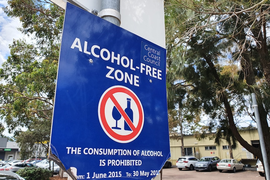 A blue alcohol-free zone sign stands in the centre of a community hub, near the new Dan Murphy's store.