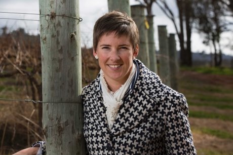 woman in warm coast standing against a farm fence