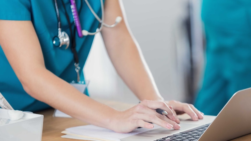 Nurse uses laptop in hospital.