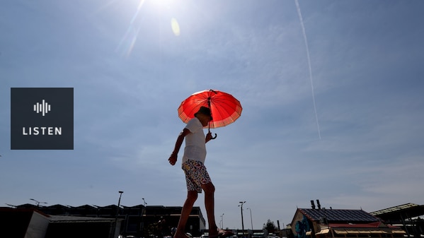 a man walking outdoors under the hot sun carrying an umbrella. Has Audio.