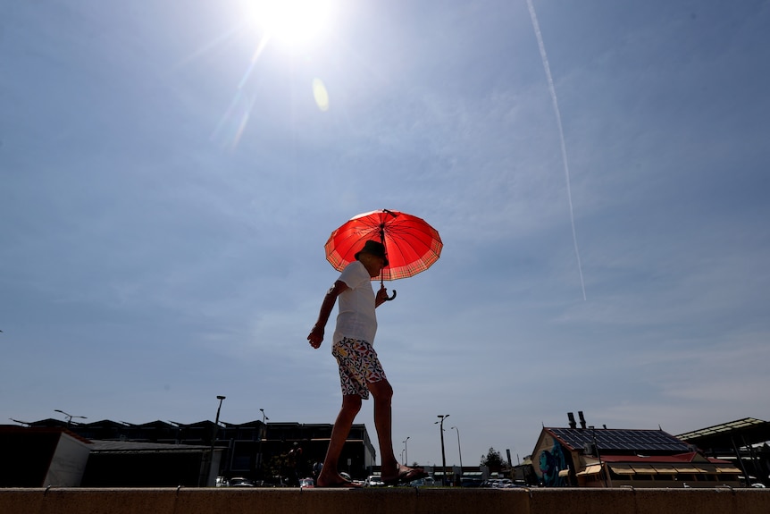 a man walking outdoors under the hot sun carrying an umbrella