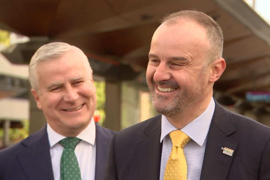 Two men in suits smiling.