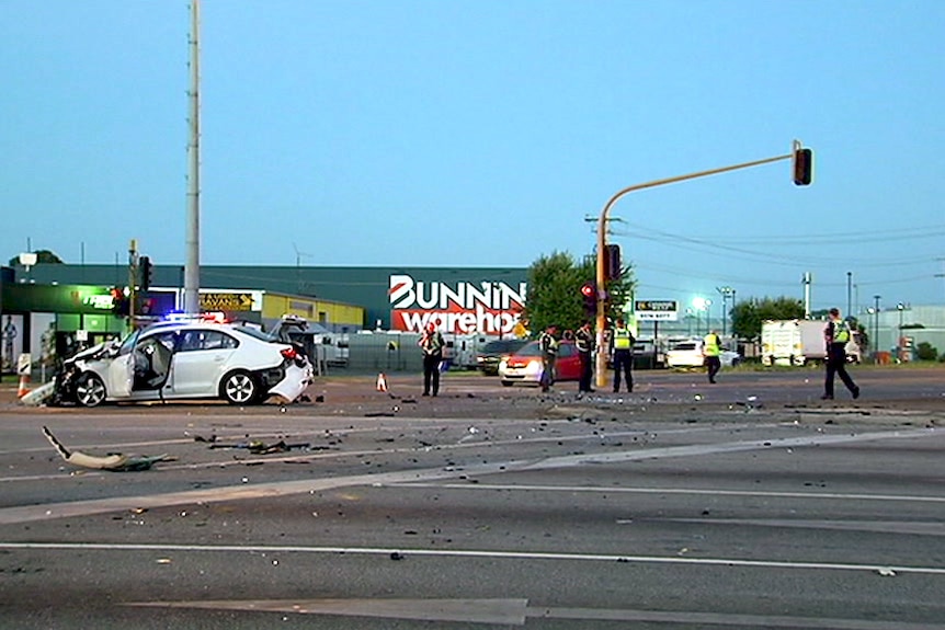 At dawn, at a major intersection, emergency services crews deal with a car crash.