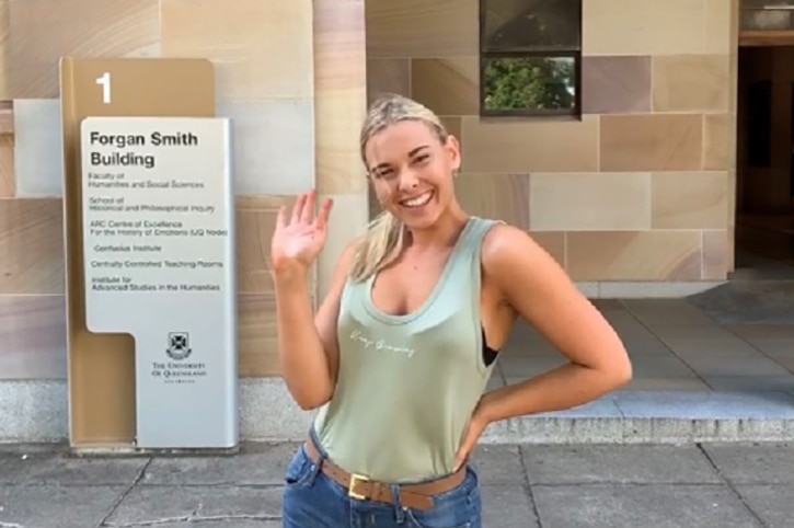 A young woman standing in front of the Forgan Smith building at the University of Queensland