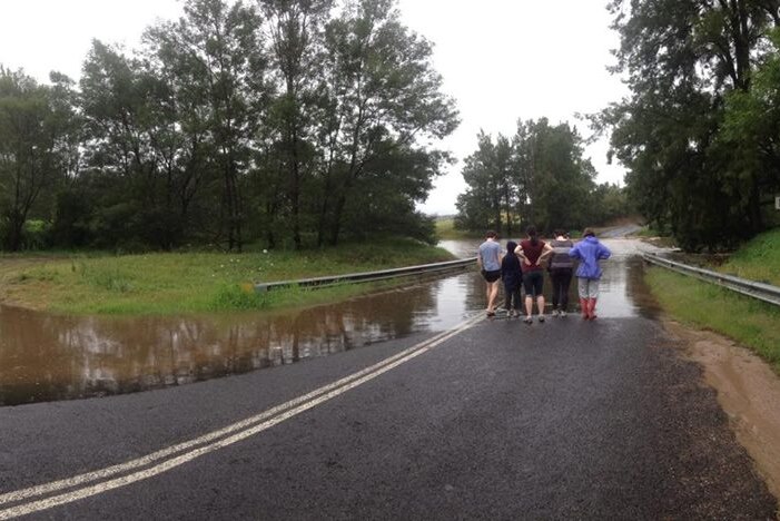Four people looking at flooding over the Kiora Bridge on the Moruya River.