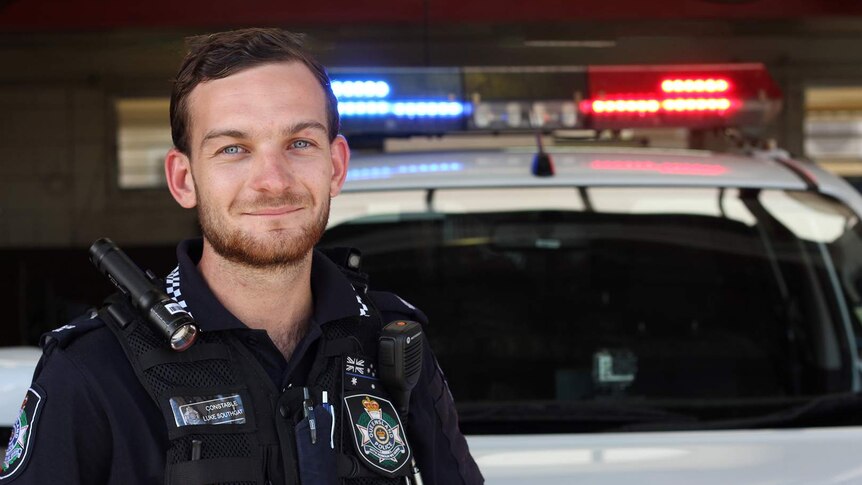 Police constable Luke Southgate leans on a police car