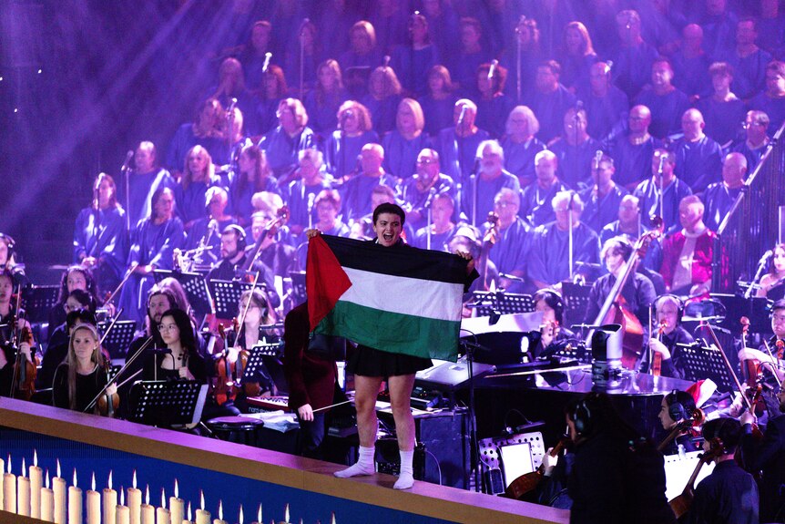 A man holding a Palestinian flag on the stage