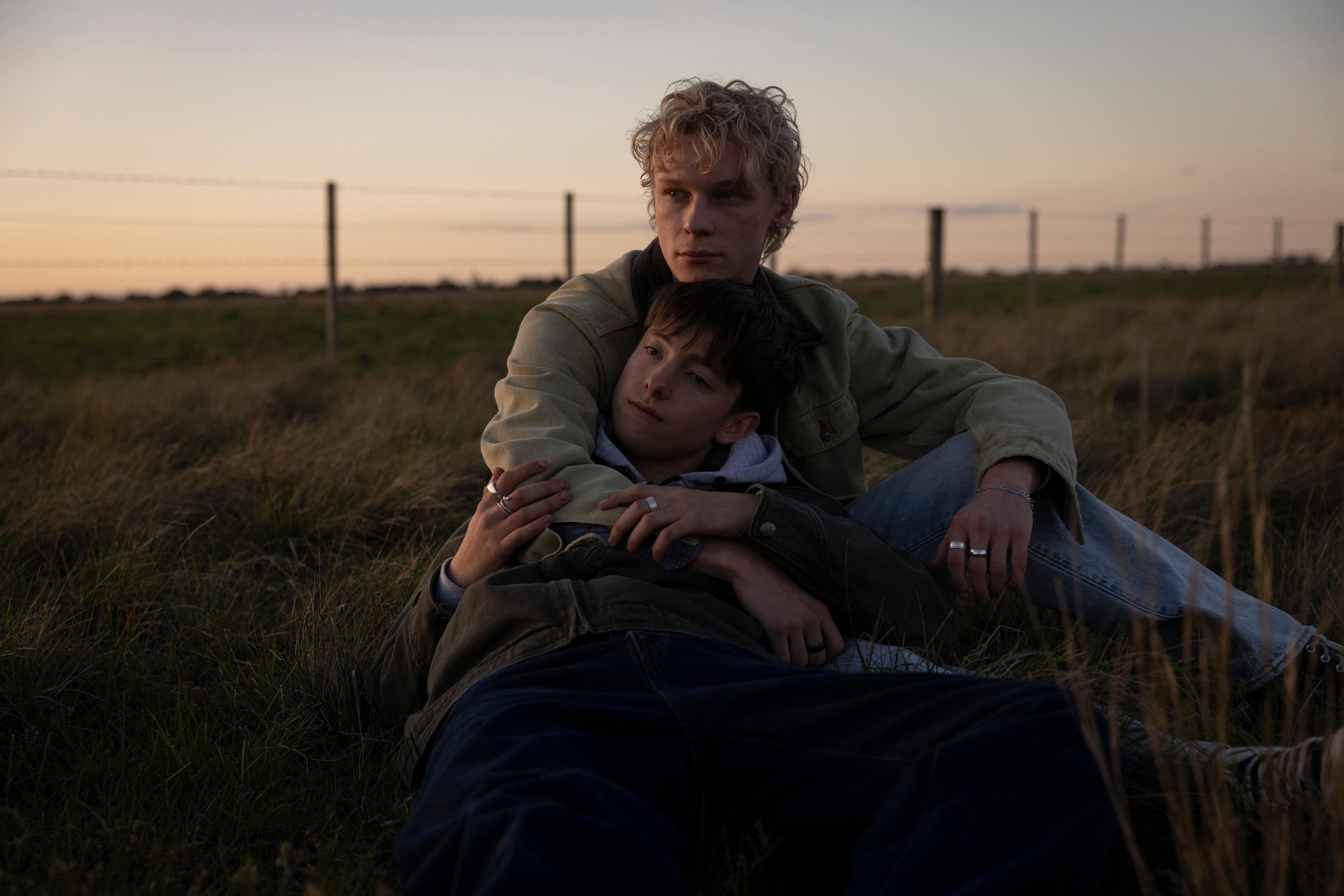 Two young men lie in a field together