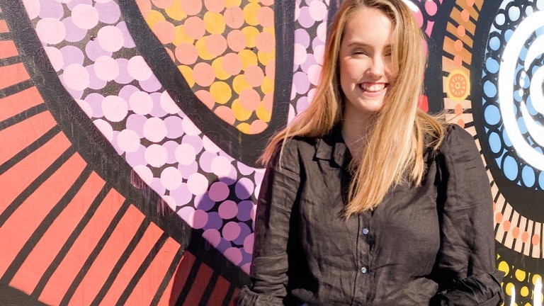 Woman standing against a colourful wall, in a story about how to harness life crisis for good.