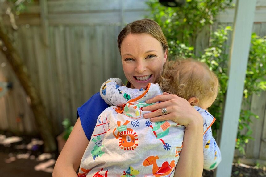 Renee Knight smiles happily, holding a baby in her hands.