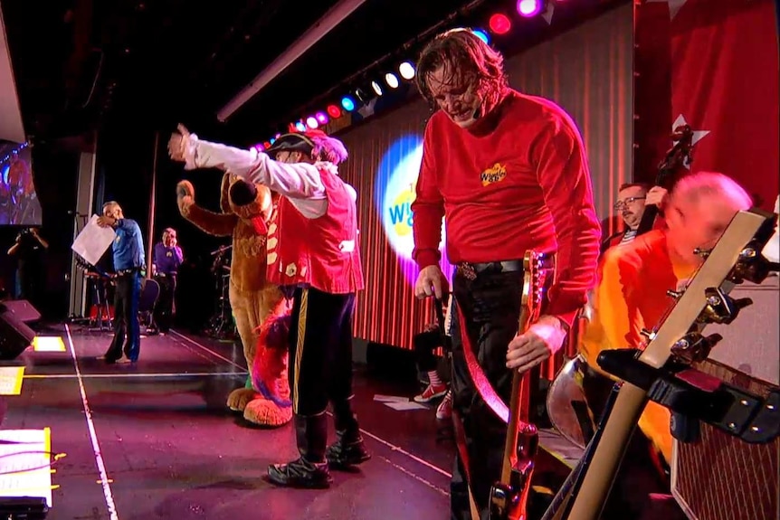 wiggles members perform as the original yellow wiggle falls to the side of the stage