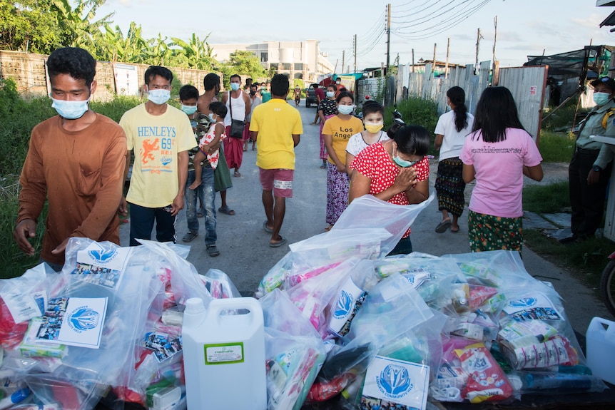 People in face masks lined up behind food packages on a Bangkok street