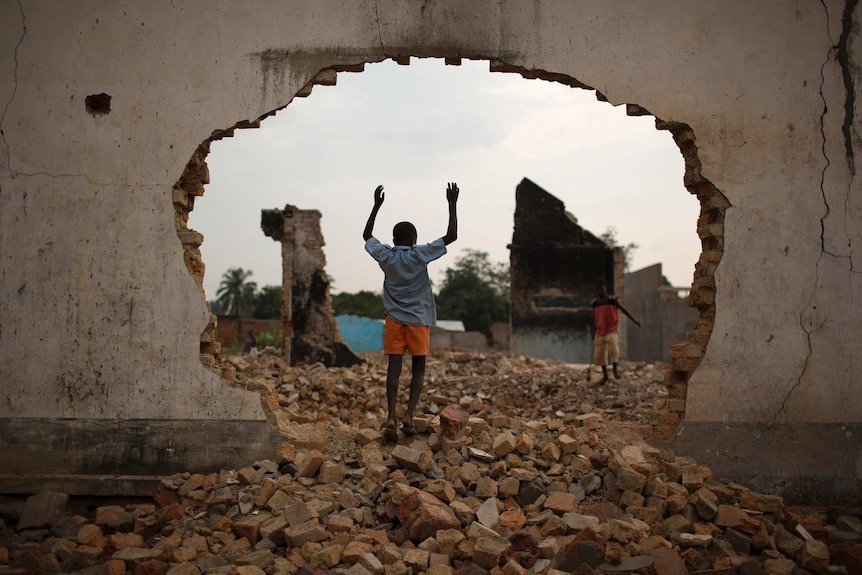 A boy plays among ruins