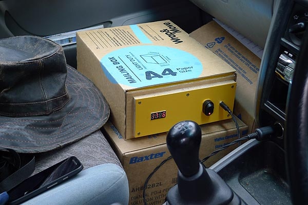 A box sits in the passenger side of a car, connected to the lighter
