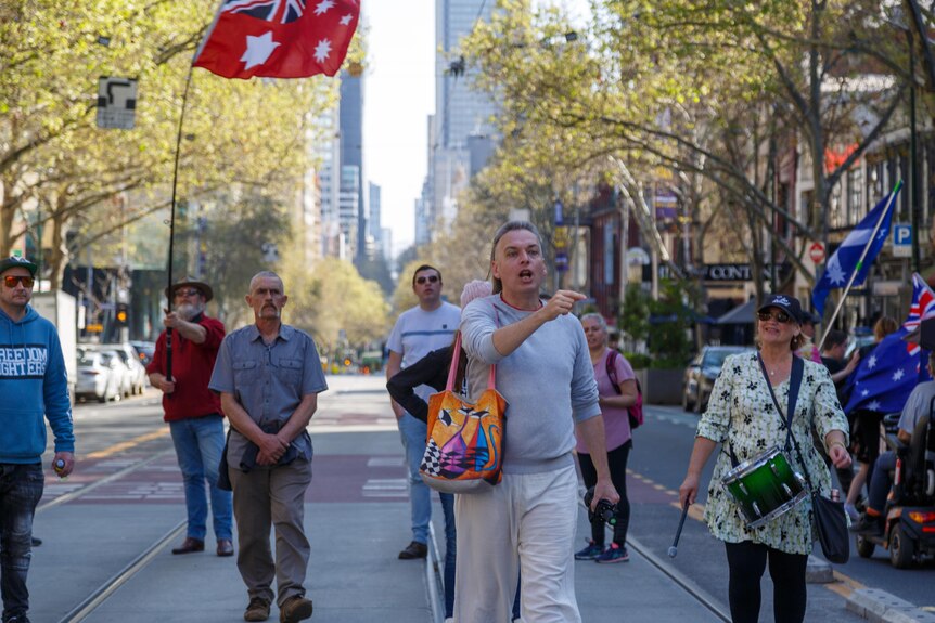 A small group of people waving Eureka and Australian flags during a protest.