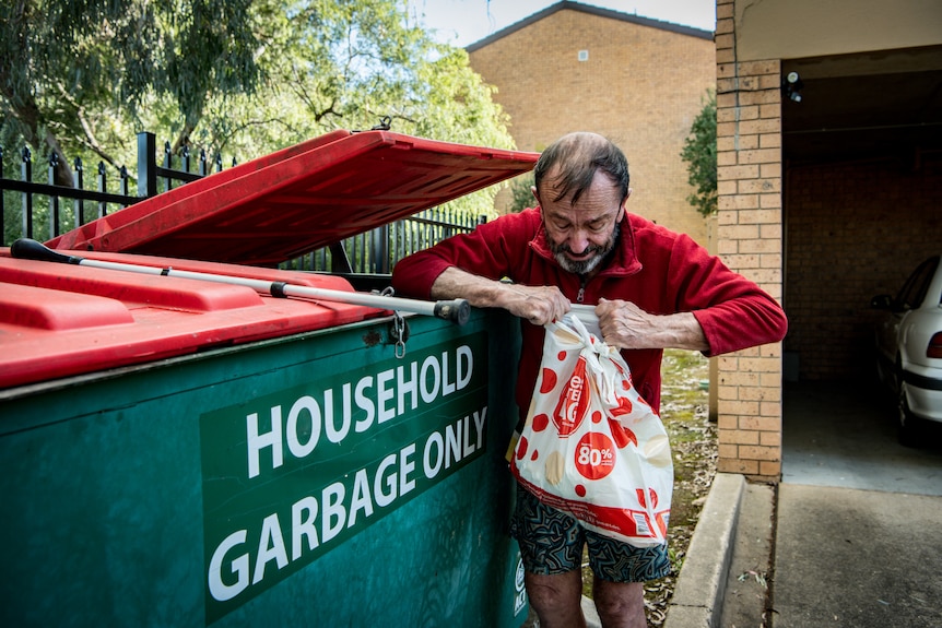 Peter Ristic looking for cans in a skip bin