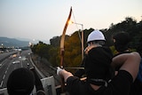 A protester uses an arrow to guide cars on the Tolo Highway outside the Chinese University of Hong Kong.