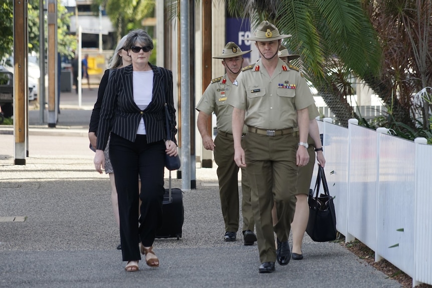 A barrister in a suit and three army officials walk outside the Darwin Local Court.