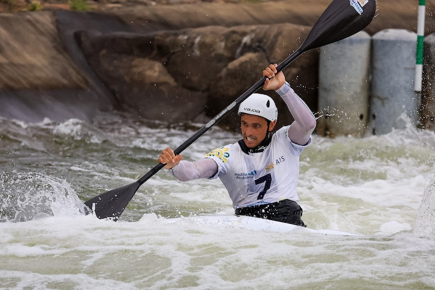 Tim Anderson is paddling during a kayak cross race, with an intense look on his face.