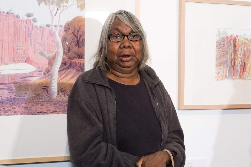 Gloria Pannka standing in front of two works by Albert Namatjira