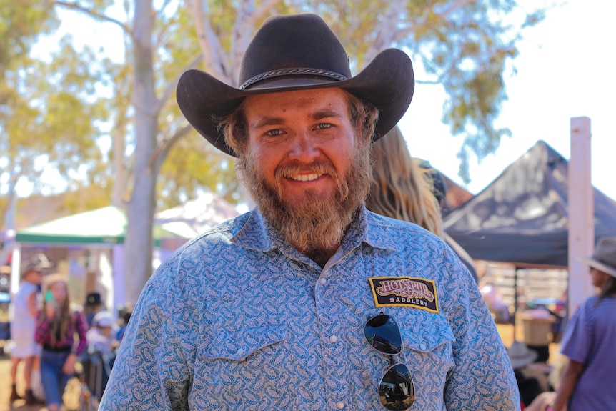 A man with a large cowboy hat, smiling broadly at a rodeo event.