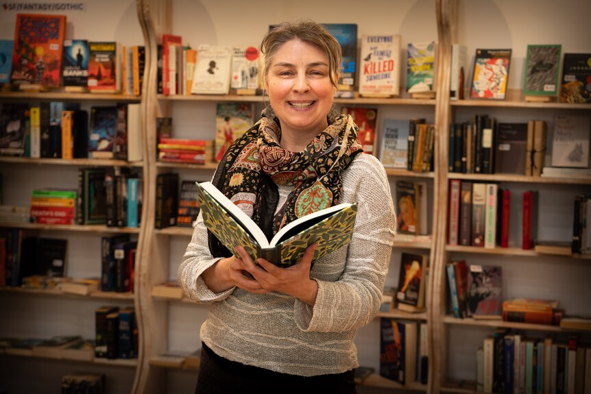 A woman smiles while reading a book.