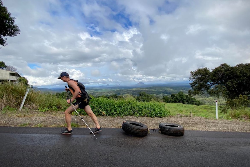 Man going up hill dragging two tyres