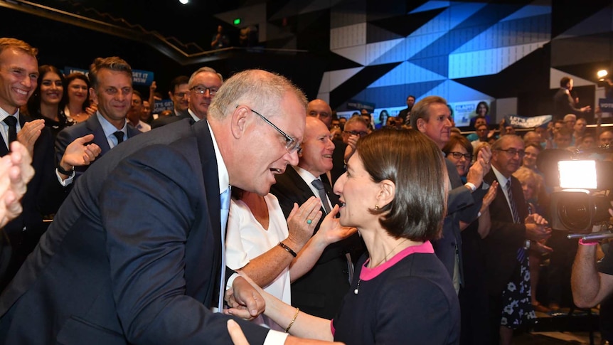 A man and a woman embrace in front of a crowd