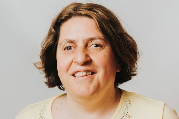 A photo of a woman with brown hair and yellow shirt.