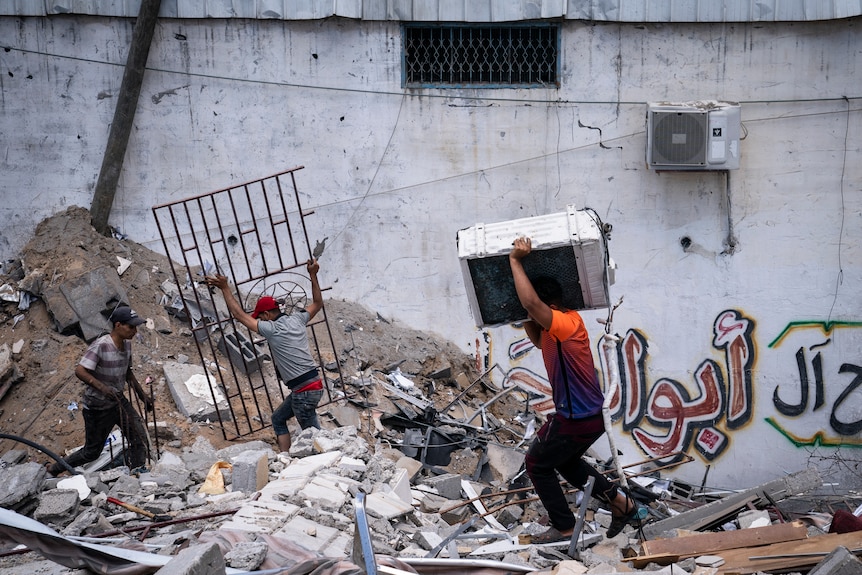 People reclaim materials from a debris pile of a building destroyed by an air strike