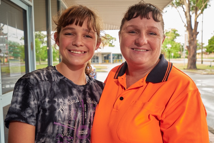 A mother and teenage daughter smile at the camera