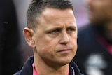 Brendon Bolton has a neutral expression on his face wearing a dark blue jacket with a lanyard around his neck