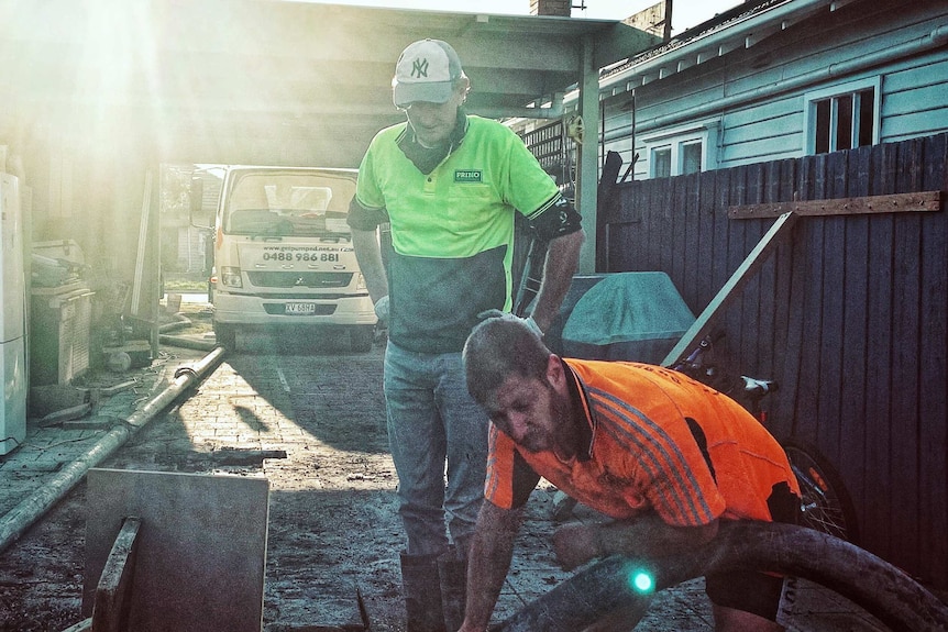 Simon O'Donnell watches over a man holding a hose.