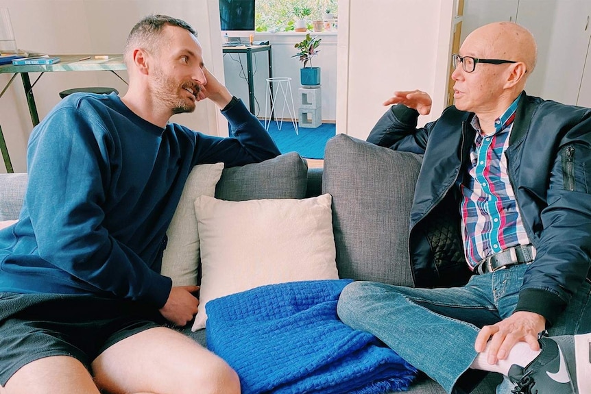 Two men sitting on a couch in conversation.