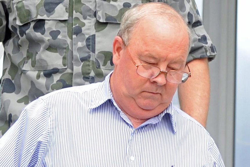 Navy officer John Jones is escorted by military police from the defence court martial rooms in Canberra on December 14, 2011.