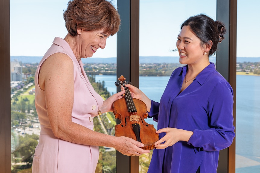 Emily Sun receiving "The Adelaide" from Ukaria's CEO Alison Beare. Behind them there is a view of the city from the window.