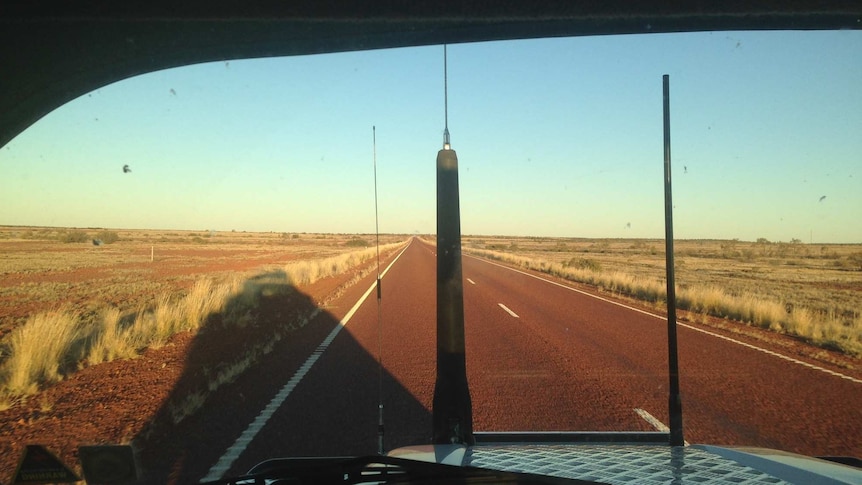 A view of a red highway stretching out from inside a ute