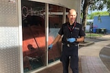 A police officer in blue rubber gloves points to the hole left in the front window pane of Groove Cafe.