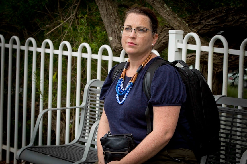 Julia Gilchrist sits on a bench under a tree. 