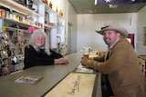 Iris stands behind the bar and serves Ryan beer who sits on the customer side