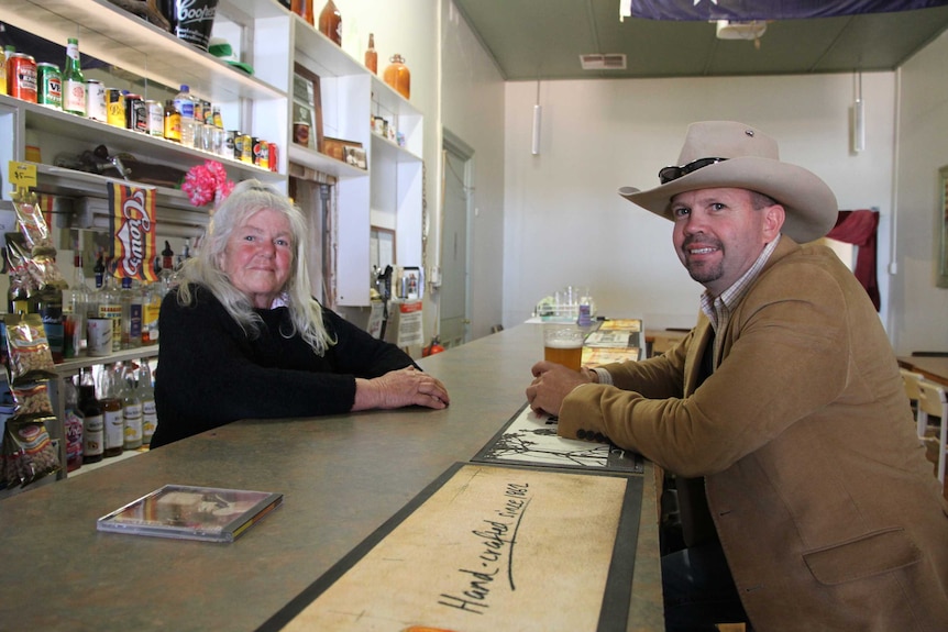 Iris stands behind the bar and serves Ryan beer who sits on the customer side