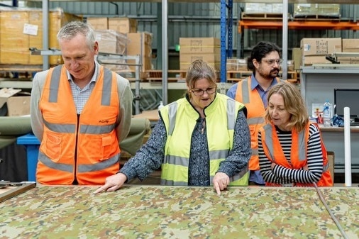 people in hi-vis vests look over army khaki uniform fabric